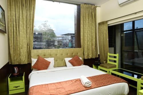 a bedroom with a bed and a large window at valparai home STAY LLHS in Vālpārai