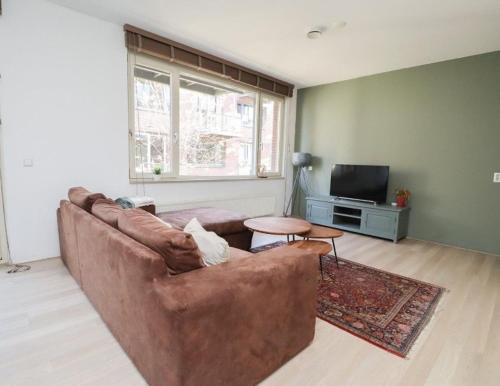 a living room with a brown couch and a tv at Spacious apartment in the heart of the city center with parking space in Breda