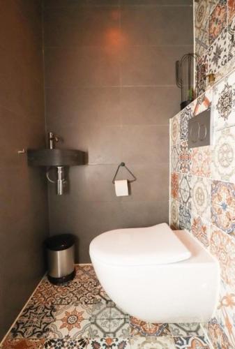 a bathroom with a toilet on a tiled floor at Spacious apartment in the heart of the city center with parking space in Breda