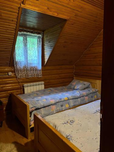 a bedroom with two beds in a log cabin at Дім-Садиба Озерел in Krasna