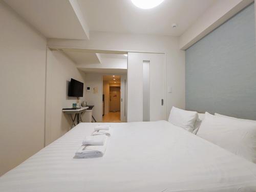 a bedroom with a white bed with white pillows at R Home Sakuragawa Riverside in Osaka