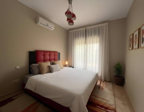 a bedroom with a large white bed with a red headboard at La Perle de Marrakech by Atlas Golf Resort in Marrakesh