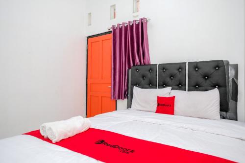 KaliangetにあるRedDoorz Syariah near Alun Alun Wonosobo 4のベッドルーム1室(大型ベッド1台、赤と白の枕付)