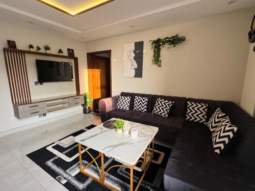 Una sala de estar con un sofá negro y una mesa. en Osma Living Apartment Lahore, en Lahore