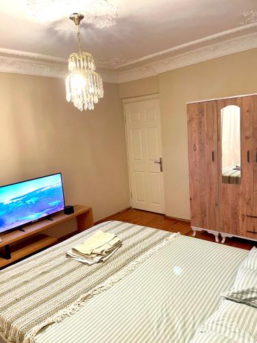 a bedroom with a bed and a tv and a chandelier at Şehrin merkezinde evinizde hissedeceğiniz oda in Konak