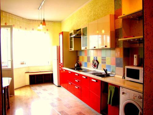 cocina con armarios rojos, fregadero y microondas en Guest House On Abdulliny Street 54 en Almaty