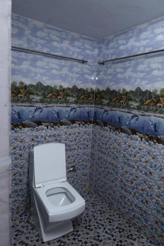 a bathroom with a toilet with a mosaic wall at valparai home STAY LLHS in Vālpārai