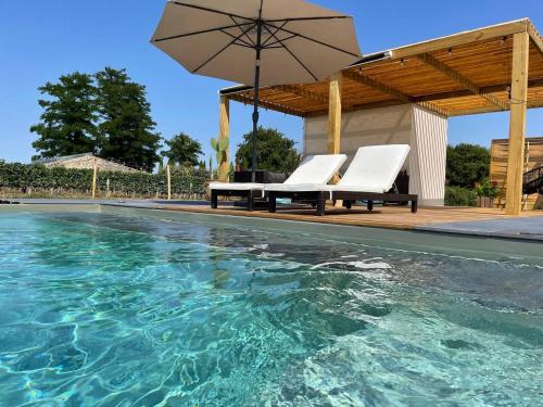 a swimming pool with two chairs and an umbrella at Chambres au cœur des vignes in Saint-Christoly-Médoc