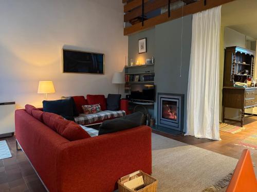a living room with a red couch and a fireplace at The Barns Low Stott Park near Lake Windermere in Ulverston