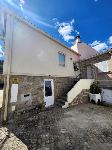 a house with a white door and stairs on it at A Casa da Aldeia 1 Belmonte in Gaia