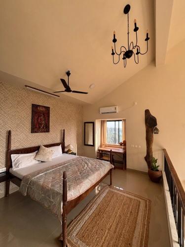 a bedroom with a bed and a chandelier at Saanjh-Kudrats Nilaya in Canacona
