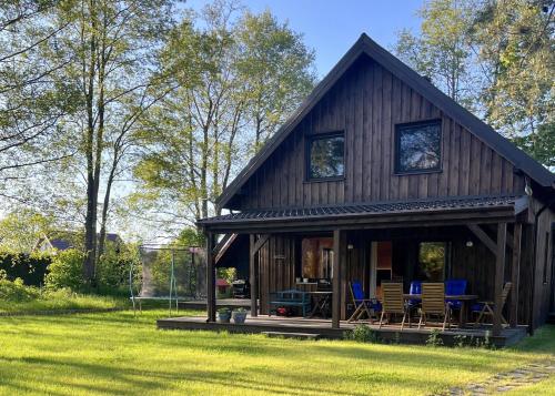 a large wooden house with chairs in a yard at Dom na Perłowej in Kopalino