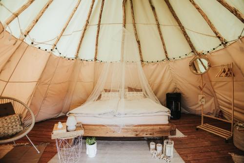 a bed in a canvas tent with a table at Teepee Svištící šíp 