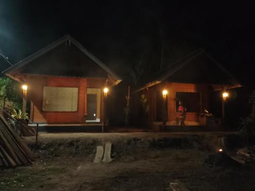 a person standing outside of a house at night at Tetebatu River Side BUNGALOWs in Tetebatu