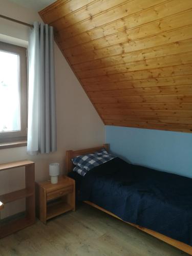 a bedroom with a bed and a wooden ceiling at Domek pod Koroną Bieszczad in Strzebowiska