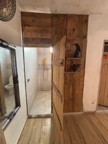 a bathroom with a wooden door and a toilet at EL Faro Surfstay in Tamri