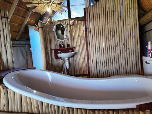 Una bañera en un baño de bambú con lavabo. en Kazondwe Camp and Lodge, en Kongola