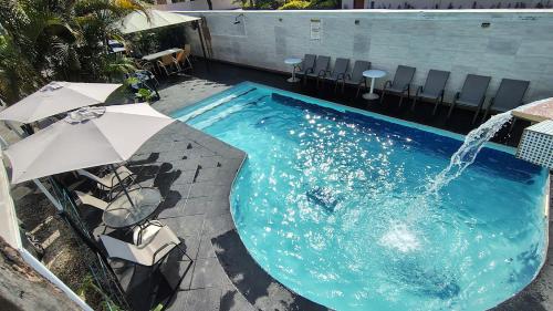 ein großes Schwimmbecken mit Springbrunnen in der Unterkunft Hotel Pousada Iracemar, 60m da Praia da Enseada, Piscina Aquecida ao Ar Livre para Relaxar em Qualquer Estação, Café da Manhã, Estacionamento, Recepção 24h, Aproveite o Mar, Passeios e Atividades Náuticas a 100 metros in Guarujá