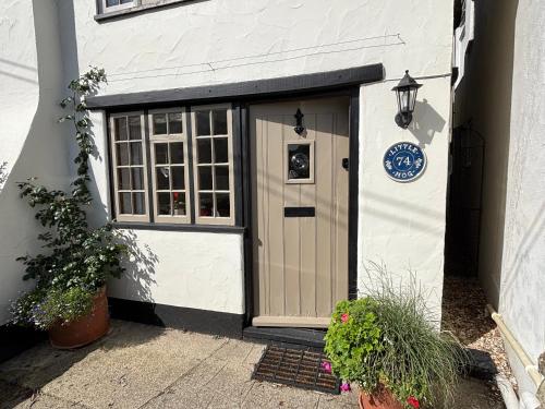 ein weißes Gebäude mit einer Tür und einem Fenster in der Unterkunft Little Hog Cottage, cosy seaside hideaway in Seaton