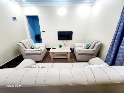 ヤウンデにあるClimatisation - Wi-Fi gratuitの白いソファと椅子のあるリビングルーム