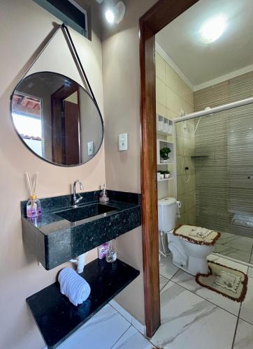 a bathroom with a sink and a mirror and a toilet at Serraruna House no centro histórico in Araruna