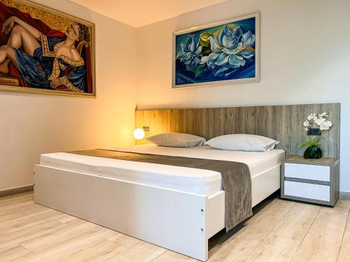 1 dormitorio con 1 cama grande con pinturas en la pared en Jata Hotel, en Tirana