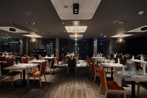 uma sala de jantar com mesas e cadeiras brancas em Thermal Hotel Balance Lenti em Lenti