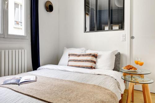 a bedroom with a bed and a table with a book at Le Marais & Place des Vosges - Paris Vacation Rentals in Paris