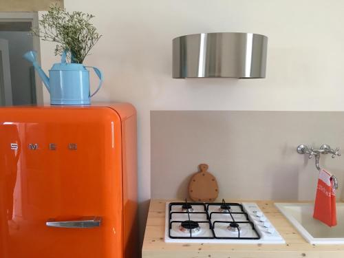 an orange refrigerator next to a stove in a kitchen at La Loggia Salentina in Poggiardo