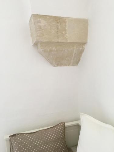 a chandelier hanging from a white wall next to a pillow at La Loggia Salentina in Poggiardo