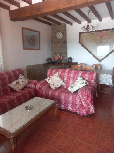 a living room with a red couch and a table at Casa Cordovilla in Sequeros
