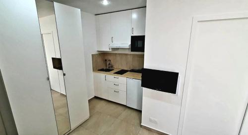 una piccola cucina con armadi bianchi e lavandino di Cosy et Chill studio Proche Paris et le Bourget , Ideal long séjour pour Couples et Professionnels a Drancy