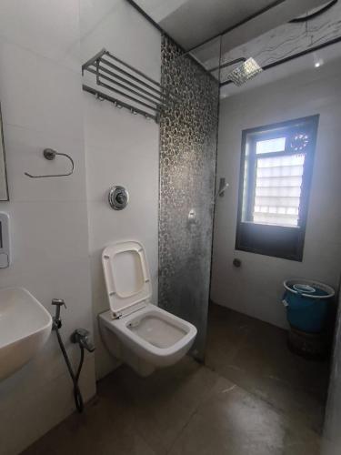 a bathroom with a toilet and a sink and a window at Hotel Shubham Inn in Thane