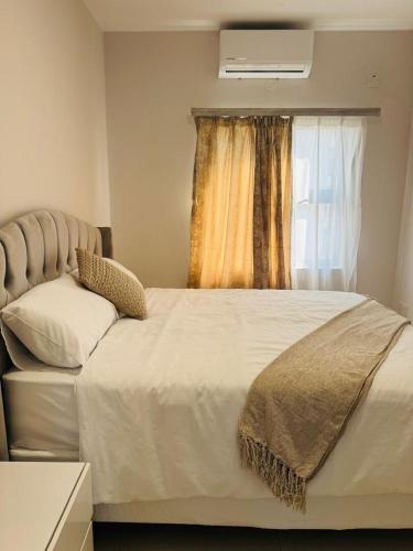a bedroom with a large bed and a window at Kastina Suites at The Fig in Gaborone