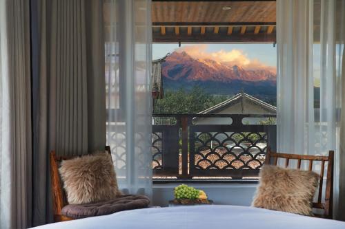een slaapkamer met uitzicht op een berg door een raam bij Dawnscape snowmountain viewing Courtyard - Baisha old town in Lijiang