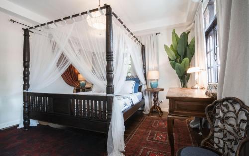 a bedroom with a canopy bed and a desk at Maprang Boutique Stay in Amphoe Koh Samui