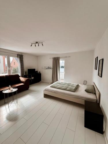 a white bedroom with a bed and a couch at P&S Home in Nordstemmen