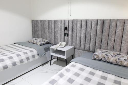 een slaapkamer met 2 bedden en een telefoon op een nachtkastje bij ريلاكس للأجنحة الفندقية in Amman