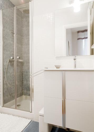 une salle de bain blanche avec une douche et un lavabo dans l'établissement Les Loges des Chalets, à Toulouse