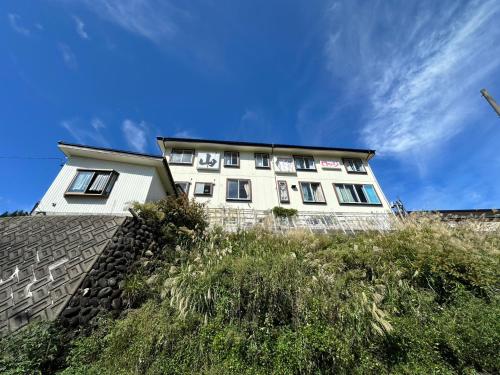 een wit gebouw bovenop een heuvel bij Bar&Lodge Duck in Gujo