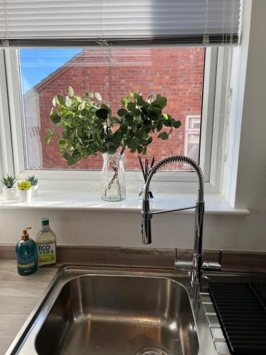 a kitchen sink with a vase of flowers in a window at Bright 2 Bedroom Apartment With Parking in Nottingham