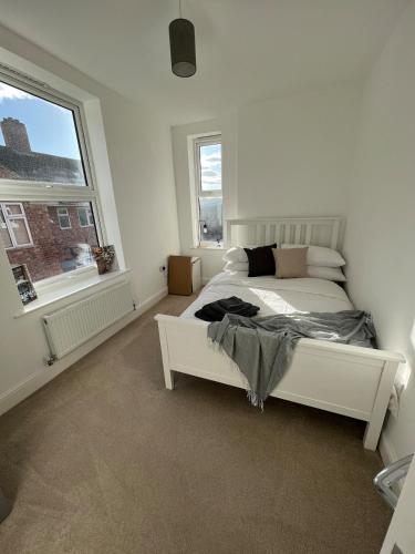 a bedroom with a white bed and two windows at Bright 2 Bedroom Apartment With Parking in Nottingham