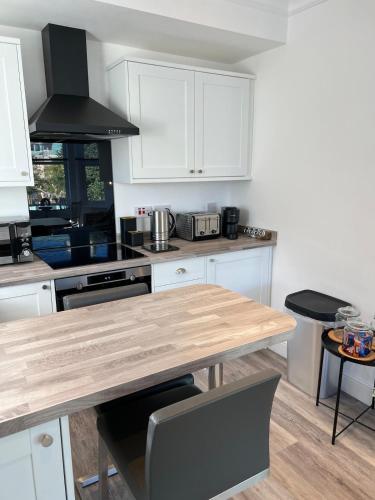 a kitchen with white cabinets and a wooden table at Bright 2 Bedroom Apartment With Parking in Nottingham