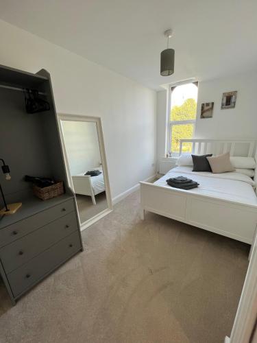 a white bedroom with a bed and a mirror at Bright 2 Bedroom Apartment With Parking in Nottingham