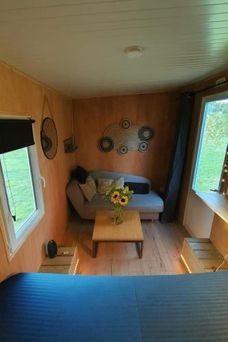 a small living room with a couch and a table at La Tiny Roulotte, hébergement insolite climatisé in Pontchâteau