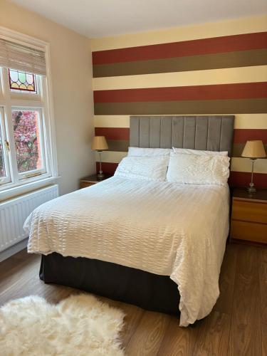 a bedroom with a large bed with a striped wall at Glenlyon Flat - NEC in Hampton in Arden