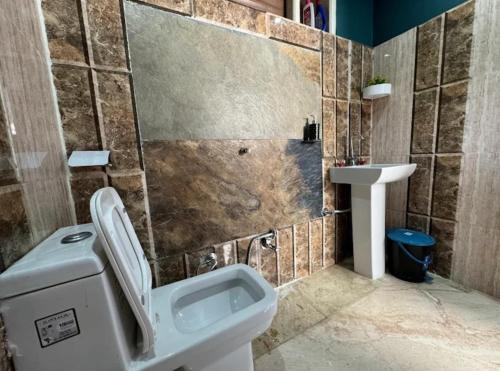 un baño con inodoro y lavabo en Atulyam Farms and Stay, en Shogi