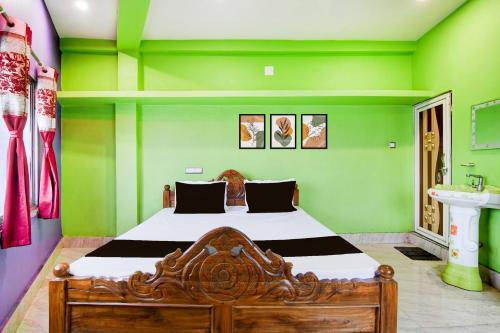a bedroom with a bed with green walls and a sink at Hotel O A R Lodge in Durgāpur