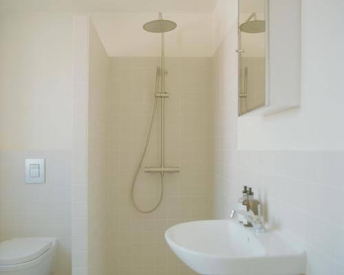 a bathroom with a shower and a sink and a toilet at Løkkenshus Rooms and Apartments in the Heart of Løkken in Løkken