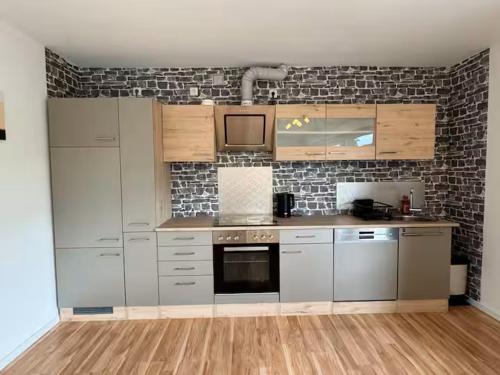 a kitchen with stainless steel appliances and a brick wall at 95qm Wohnung für 6, 3 Schlafzimmer, ruhig & stadtnah, Parkplatz in Bad Hersfeld